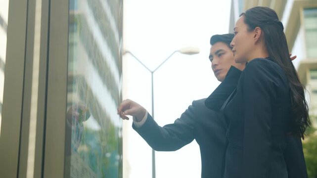 ガイドマップとスマホを見て場所を確認する男女ビジネスパーソン