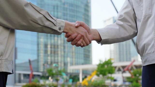 建設現場で握手する男女エンジニアのグループ