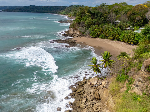 Aerial view of the rugged coastline where the turquoise ocean meets the verdant jungle, a serene blend of nature's raw beauty, Tango Mar, Puntarenas Province, Costa Rica.
