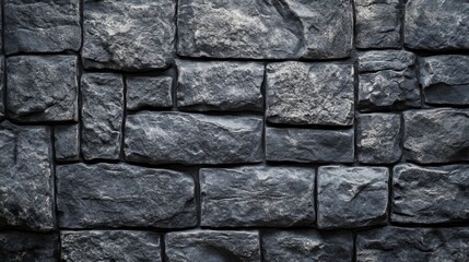 Obraz premium A textured wall made of irregular dark stones in varying sizes and shapes