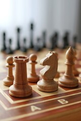 A vertical close-up of wooden chess pieces on a board with the opposing black army blurred in the background. Concept of strategic defense. © Helga P-A.