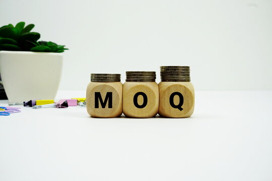 Stack of coins with wood blocks with "MOQ (Minimum Order Quantity)" Financial concept