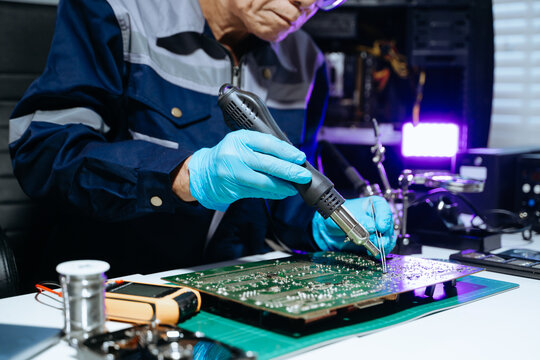 Senior technician performing PCB soldering and diagnostics with multimeter in electronics lab, showcasing hardware engineering