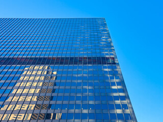 Tall building reflects sunlight against a clear blue sky in an urban setting during the afternoon hours