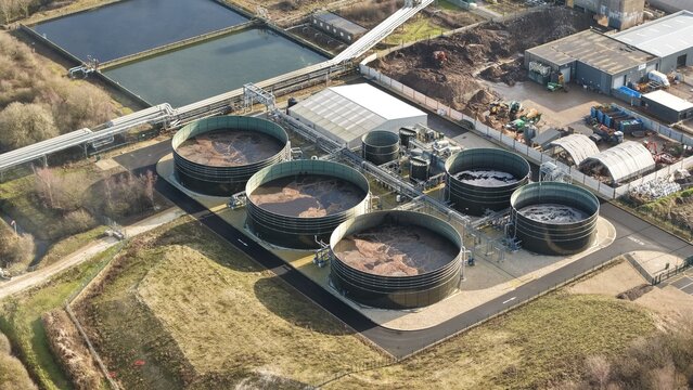 Aerial view of circular industrial tanks contrasting against the surrounding green and brown landscape, Lenzing Fibers, Grimsby, England, United Kingdom.