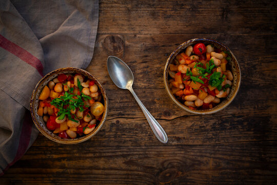 Vegetarian bean stew with herbs and vegetables on rustic wooden table