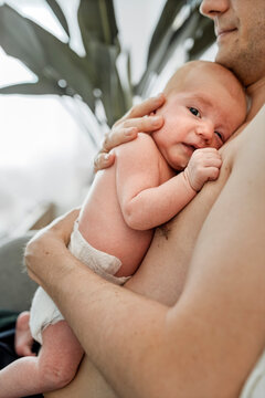 Father holding newborn baby in tender bonding moment at home
