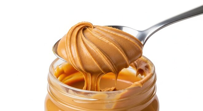 A spoon scoops creamy peanut butter from a glass jar on a white background