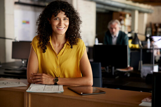 Smiling team member at creative workspace with colleague in background
