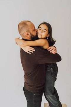 Father hugging and kissing daughter expressing family affection