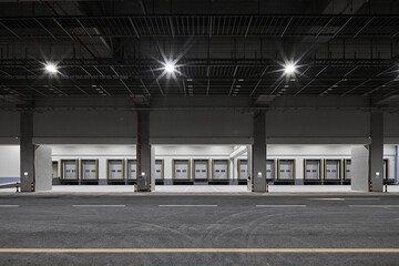 Industrial loading dock area with concrete columns and overhead lights.