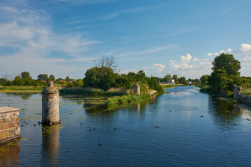 Obraz premium Wide view of the historic Stone Lock (Kamienna Sluza) and the Motlawa River with ducks under a blue sky, Gdansk, Pomerania, Poland, Europe.