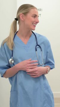 Vertical video: Coworker cue, nurse in scrubs talking and gesturing in imaging, steth watch CTXRAY