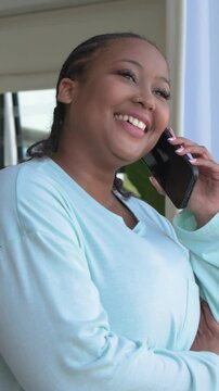 Vertical video: Taking call, woman in mint top listening then laughing at door, phone at ear