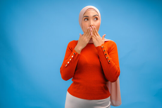 Serious Asian Muslim woman wearing veil hijab gesturing silence with her hand.
