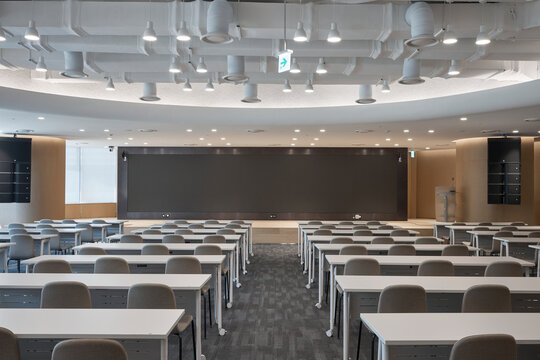 Empty modern classroom or lecture hall interior with rows of seats and ceiling lighting.