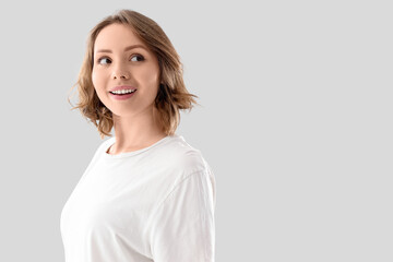 Obraz premium Beautiful young woman with short curly hair on light background