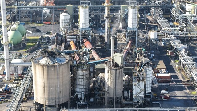 Aerial view of a sprawling industrial complex with silver tanks and a network of pipes under a hazy sky, Humber Refinery, Immingham, United Kingdom.