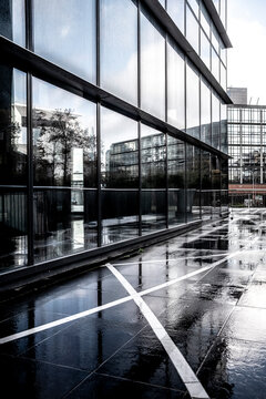 Glass architecture facade with wet pavement reflection and graphic lines in La Defense Paris showing modern business district design