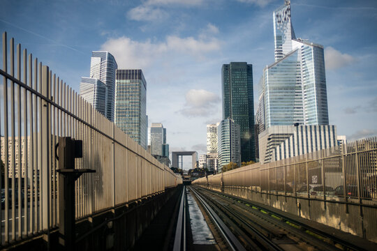 Railway tracks perspective toward modern business architecture skyline in La Defense Paris showing urban corporate district and transit lines