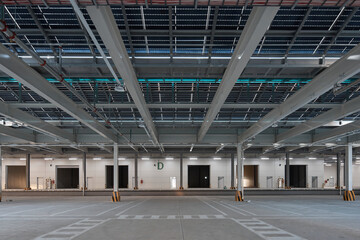 Fototapeta premium Empty large warehouse interior with concrete floor, columns, and industrial lighting.