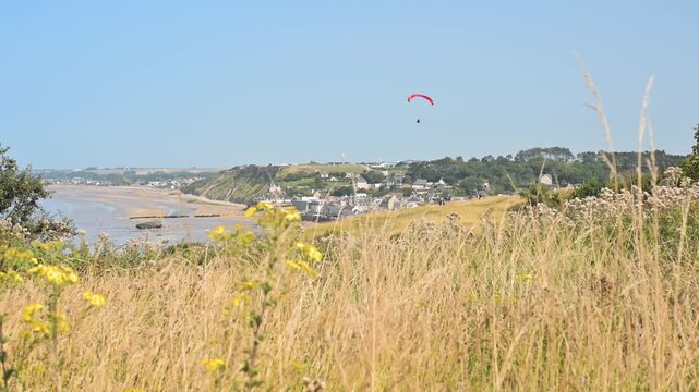 Static shot of colorful paragliders spread across the cliffs of Arromanches