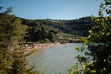 Scenic Mediterranean bay with a crowded beach and clear turquoise water on a sunny day