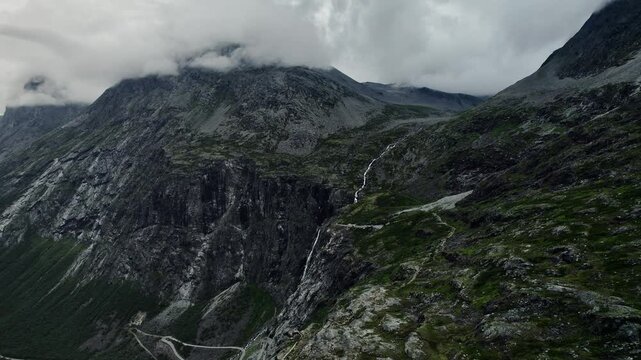 Drone captures the 280 meter Trollfossen waterfall on the Tverelva river, Storgrovfjellet mountain shrouded in clouds, and Isterdalen valley in M&oslash;re og Romsdal county, Norway.
