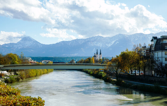 Villach, Austria - November 06, 2023: Scenic view of a river Drau with a bridge, mountains in the background, and a church tower visible in the picturesque landscape