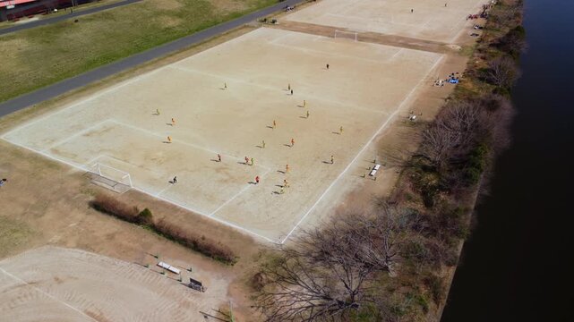 土手沿いのコートでサッカーをする少年を空撮　4K