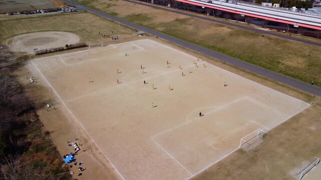 土手沿いのコートでサッカーをする少年を空撮　4K