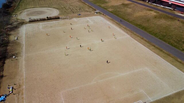 土手沿いのコートでサッカーをする少年を空撮　4K