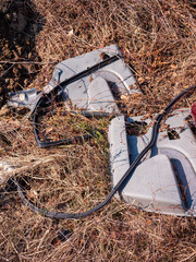 Nelegálne vyhodené plastové autodiely v prírode. Plastová výplň dverí auta a gumové tesnenie pohodené na zemi v krajine. © Marek