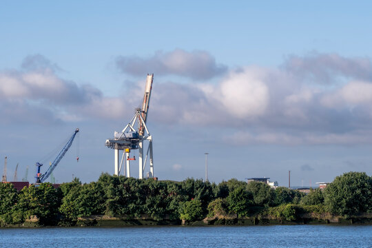 Hamburg Germany harbor waterfront with port crane industrial shipping logistics and skyline across the water in clear daylight