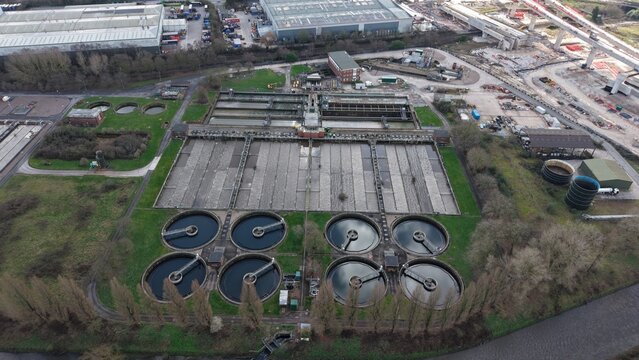 Aerial view of the water treatment plant and its intricate circular and rectangular structures, with a new construction site in the background, Coleshill, United Kingdom.