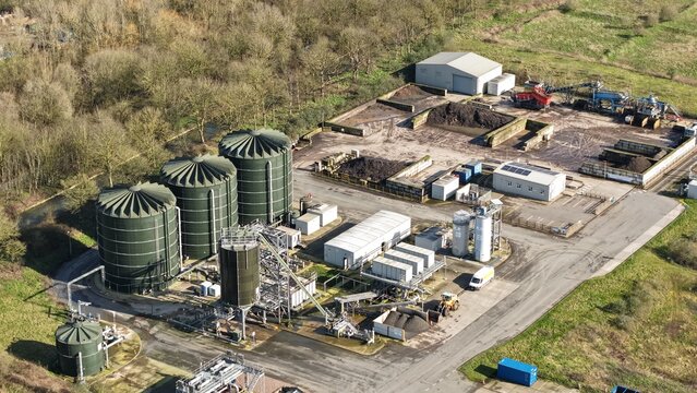 Aerial view of industrial tanks gleaming under the sun, juxtaposed with earthy piles of compost, creating a stark contrast of man-made structures and organic materials, Coleshill, United Kingdom.