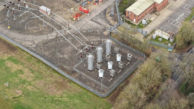 Aerial view of the National Grid Hams Hall Substation, where power lines converge amidst stark industrial architecture, Birmingham, United Kingdom.