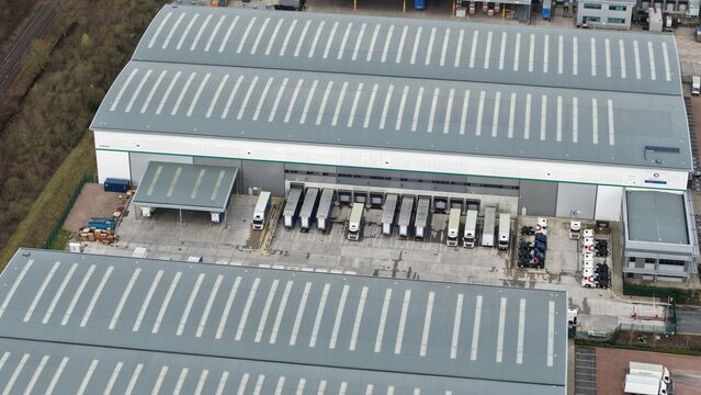 Aerial view of industrial buildings with rows of trucks parked outside creating a scene of organized activity, Birmingham, England, United Kingdom.