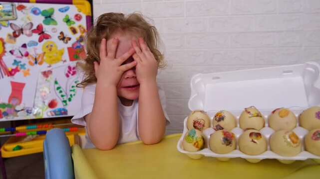 Moscow, Russia, 12.04.2025 A young child is sitting at a table with a dozen yellow eggs in front of him. He is crying and covering his eyes