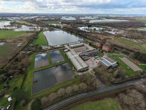 Aerial view of the serene water treatment plant nestled amidst verdant fields and reflective pools under a cloudy sky, Birmingham, England, United Kingdom.