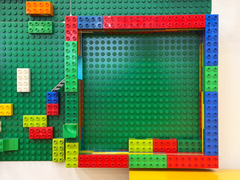 Colorful toy brick square frame on green baseplate