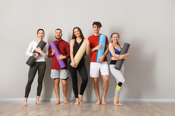 Obraz premium Group of sporty people with yoga mats near light wall in gym