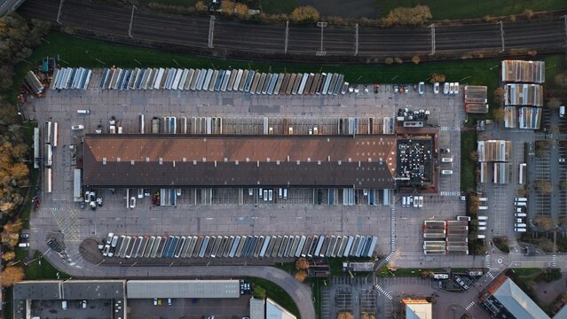 Aerial view of the FedEx Unit 24 warehouse with orderly rows of parked vehicles casting long shadows in the Holly Lane Industrial Estate, Atherstone, United Kingdom.