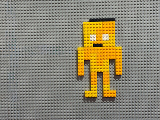 Naklejka premium Yellow brick pixel-robot on gray baseplate