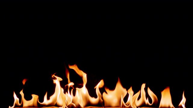 Slow motion flames dancing against a deep black background, creating a dramatic and powerful fire effect. Abstract burning fire with glowing orange and yellow tongues of flame, ideal for backgrounds. 