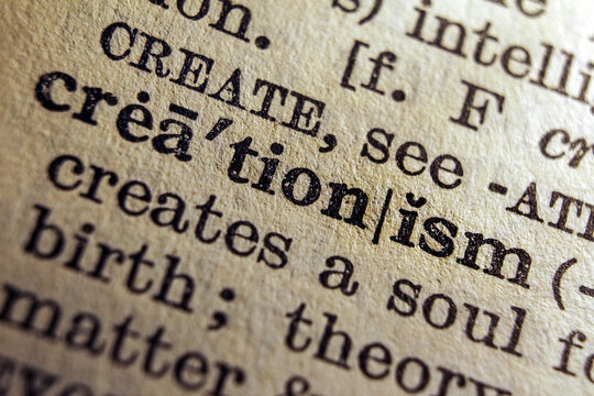 Word creationism printed on dictionary page, macro close up