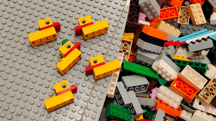 Naklejka premium Multiple small yellow and red LEGO plastic duck models arranged on a grey baseplate next to a pile of colorful building bricks on January 3, 2026 in Bangkok, Thailand.