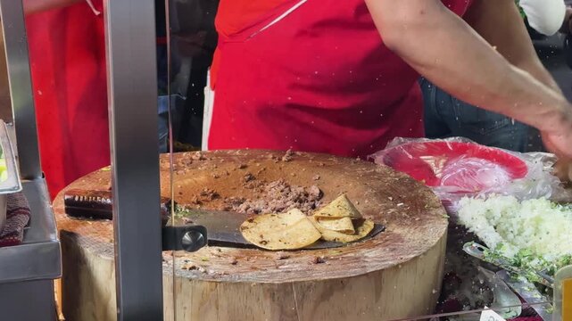 Street vendor makes suadero and longanisa tacos, lively atmosphere