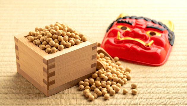 Japanese setsubun festival celebration with roasted soybeans in a traditional wooden masu box and a red oni demon mask on a tatami mat.