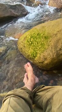 POV of a barefoot traveler relaxing in a clear mountain stream flowing through rocks at sylhet, bangladesh.